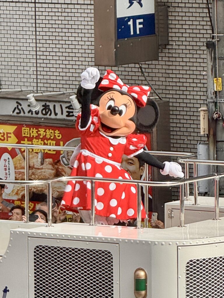 パレードの車の上で右手を挙げているミニーマウス
